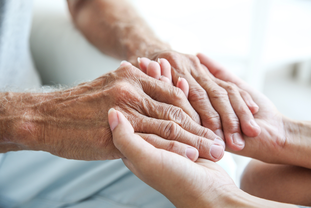 elderly hands being held by caregiver's hands