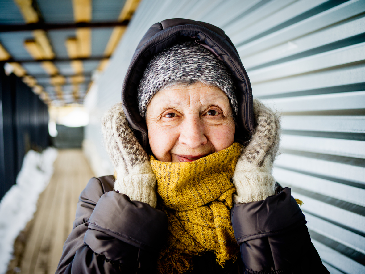 Elderly woman bundled up in a coat hat scarf and gloves for winter