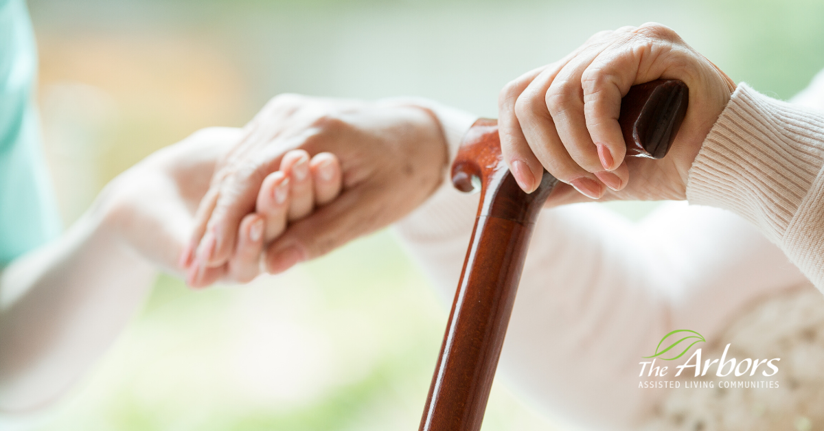 elderly woman holding can in left hand and a caretaker's hand in the right.